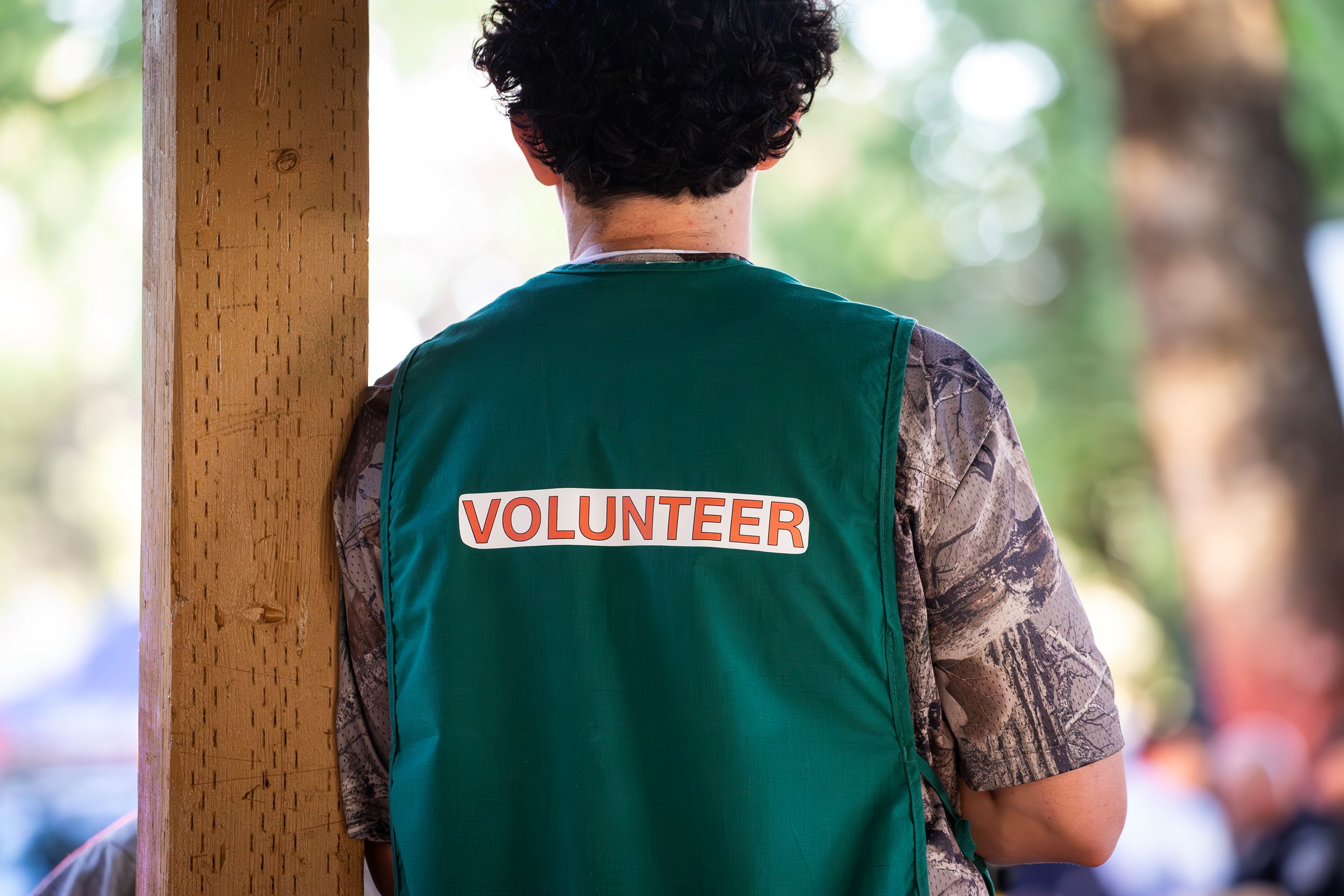 Person standing with green volunteer vest